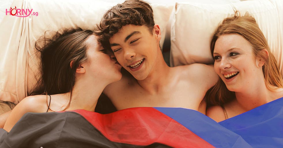 2 females and 1 male having a threesome in bed